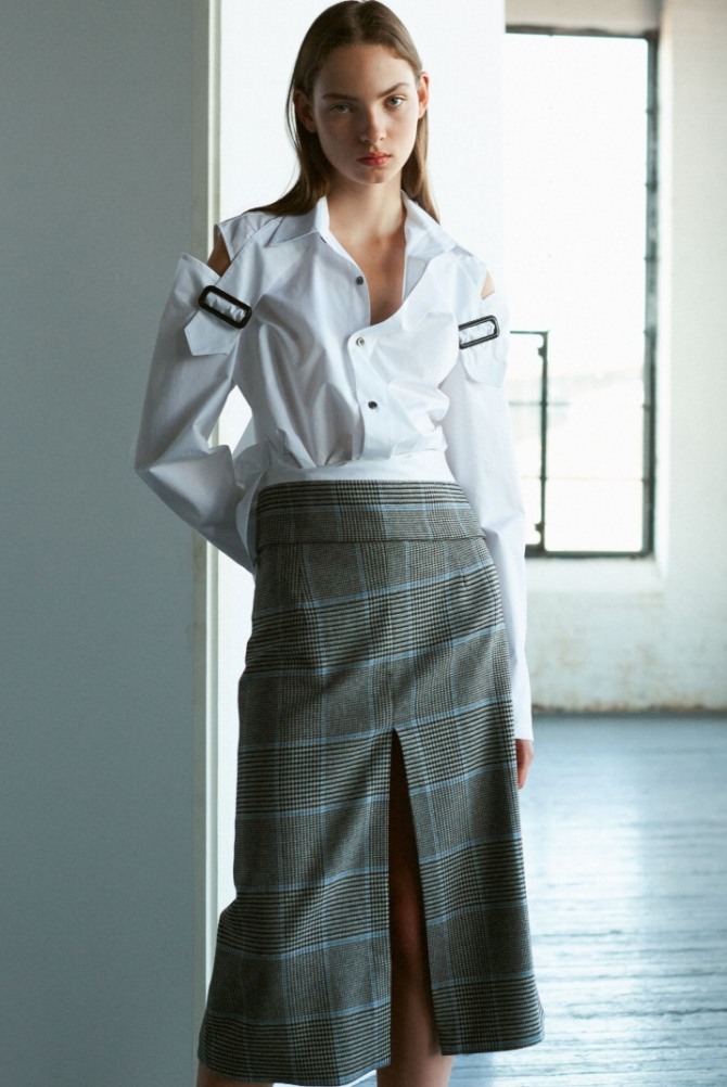 летний офисный образ 2019 - блузка с вырезами на плечах белого цвета и юбка прямого кроя в клетку с разрезом