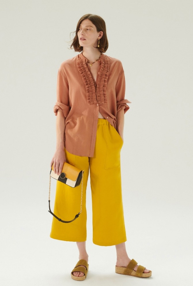 летняя блузка с рюшами светло-коричневая с закатанными до локтя рукавами в ансамбле с укороченными желтыми летними брюками