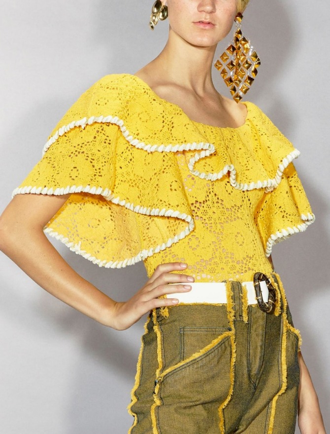 блузка желтого цвета из тюля без застежки с воланами на рукавах и круглым вырезом, заправленная в брюки