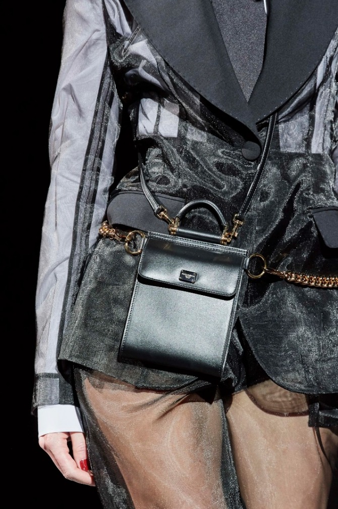 черная кожаная набедренная модель сумки, закрепленная металлическими цепочками и кожаными ремешками 