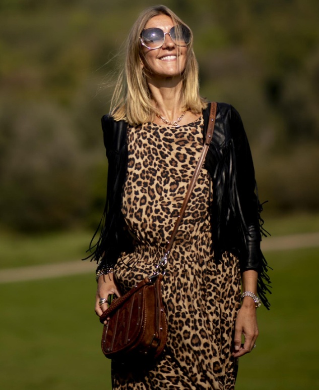 дама в возрасте в пятнистом леопардовом платье и черном кожаном пиджаке с бахромой