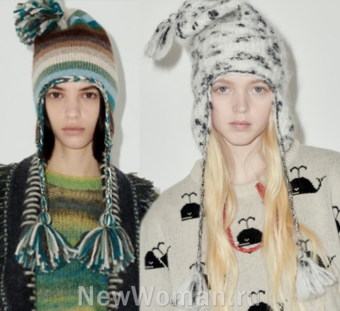 горячий тренд зимней женской моды 2023 в аксессуарах для девушек - вязаные принтованные шапки-шлемы с помпонами, гребнем, длинными завязками с помпонами на концах
