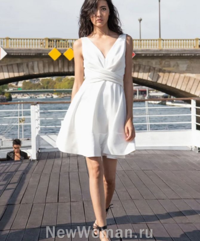 летнее платье 2024 белого цвета выше колена, без рукавов, с глубоким вырезом и драпировкой на лифе, с поясом из двух широких перекрещенных полос, юбка пышная