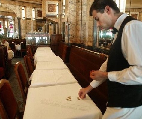 официант собирает со стола в ресторане монеты - чаевые