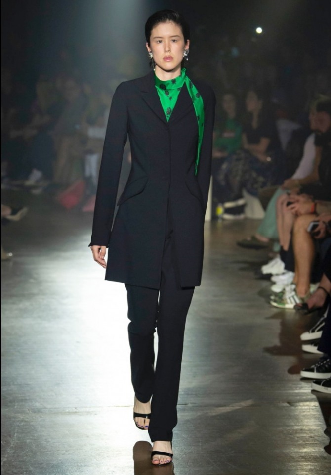 элегантное недлинное черное женское пальто в мужском стиле в комплекте с блузкой зеленого цвета