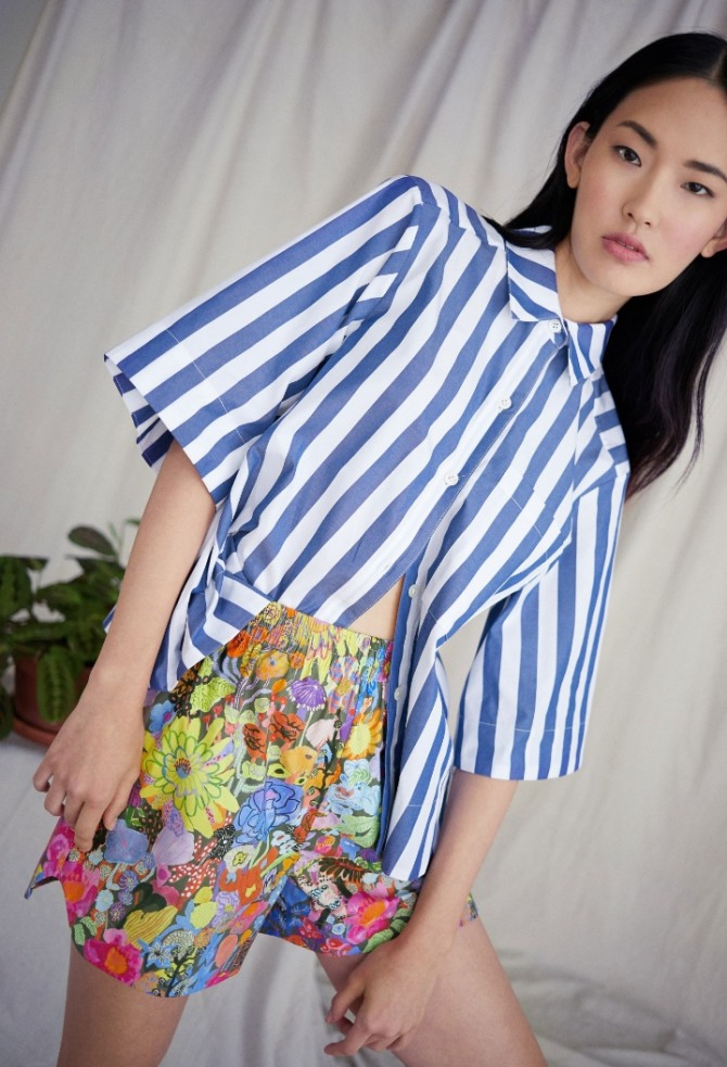 модель летних шорт с ярким цветочным принтом в ансамбле с блузкой-рубашкой с коротким рукавом, воротником и застежкой на пуговицы