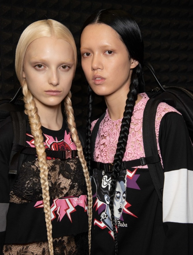 две девушки брюнетка и блондинка с заплетенными по обеим сторонам косами - модели с подиума осень-зима 2019-2020