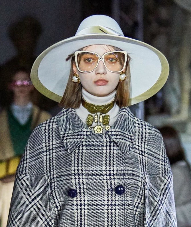 светлая шляпа с широкими полями и высокой тульей 2020 года от Gucci к клетчатому серому пальто-кейпу