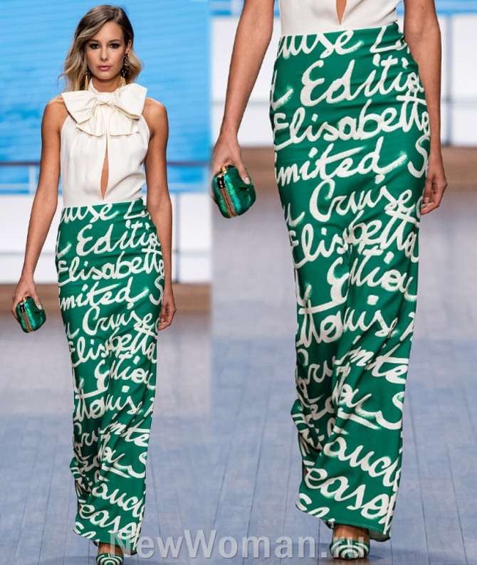 красивый вечерний летний образ 2020 от бренда Elisabetta Franchi - длинная юбка макси карандаш зеленого цвета с принтом граффити белого цвета в комплекте с нежной светлой блузкой без рукавови с большим бантом на шее и глубоким вырезом на груди