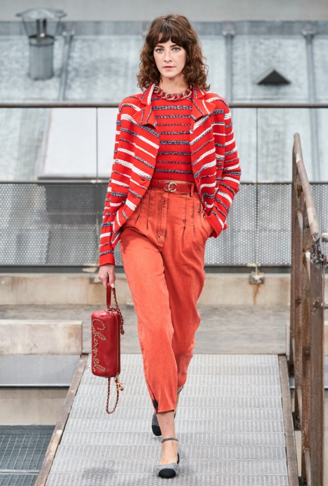 монолук в красном цвете - жакет в полоску, джинсы с застроченными складками на уровне бедер, красный кожаный ремень, джемпер с блестящими полосами, сумка-бревно, серо-серные туфли с ремешком вокруг лодыжки - фото с модного показа Chanel (неделя моды в Париже Весна-Лето 2020)