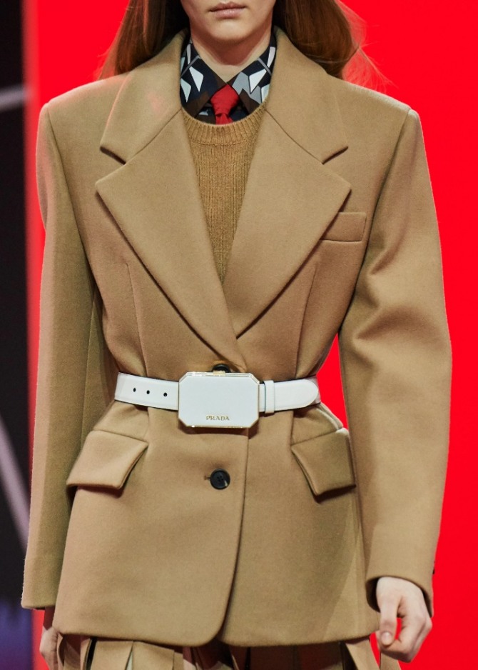 жакет бежевого цвета от Prada осень-зима 2020-2021 с белым кожаным ремнем на талии и изящной миниатюрной поясной косметичкой-клатчем