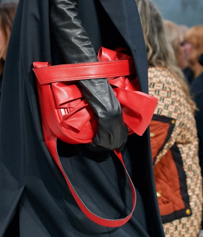 ручная дамская сумка из кожи красного цвета с большим бантом и широкой горизонтальной полосой, фиксирующей кисть руки
