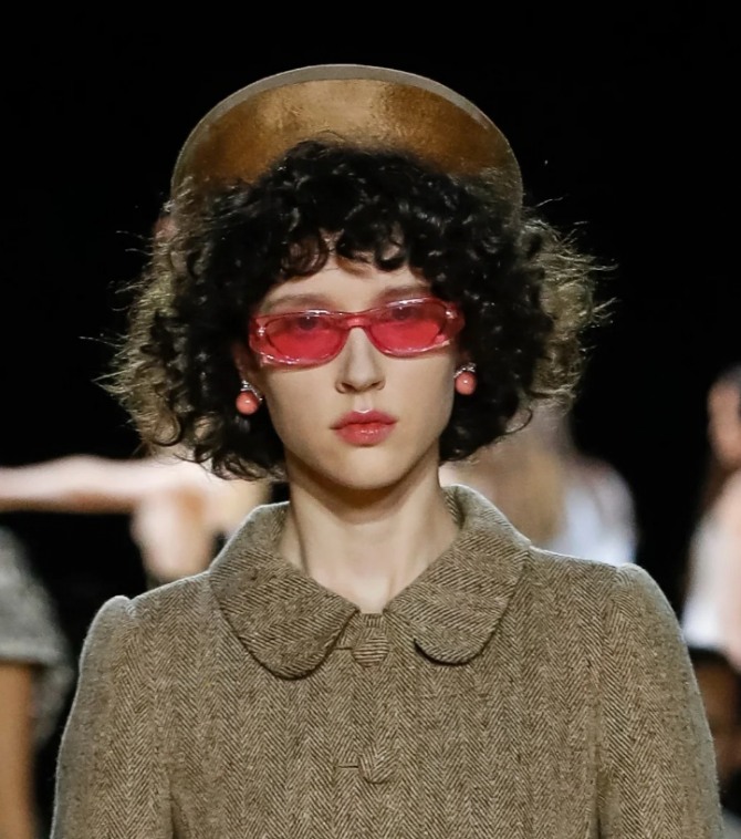 стильный осенний образ 2020 года - драповое пальто и шляпка в коричневой палитре, очки с красными линзами и бижутерия того же цвета - лук с модного показа осень-зима 2020-2021 Marc Jacobs