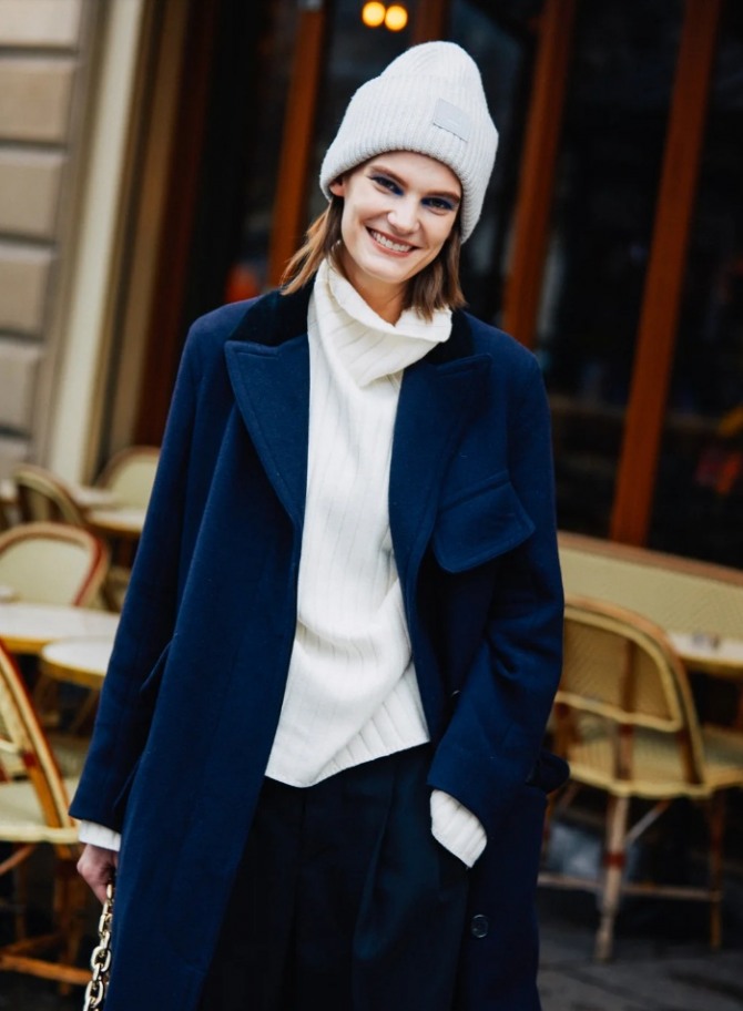 зимняя уличная мода 2021 года - синее пальто с белым свитером и вязаной шапкой