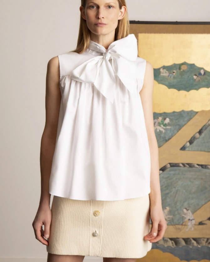 белая блуза в форме трапеции на присборенной кокетке - без рукавов, с бантом-гастуком на шее в комплекте с короткой трикотажной прямой юбкой -стильный женский образ 2022 года