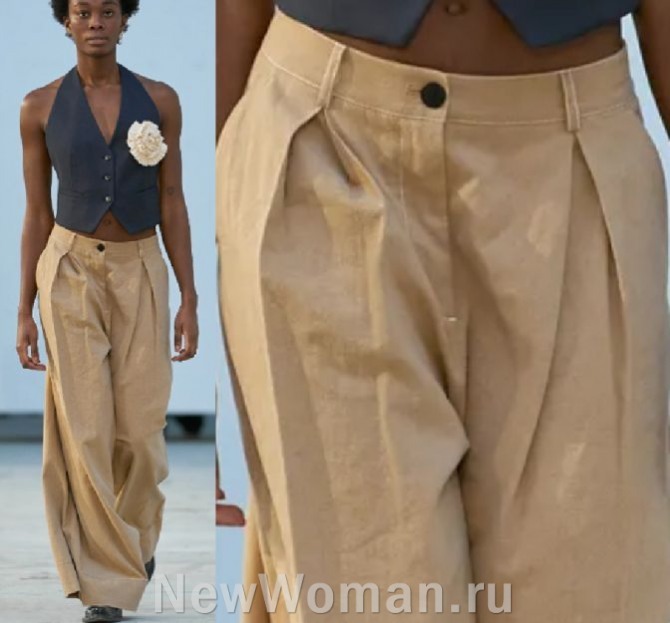 женские брюки клеш 2024 года бежевого цвета со встречными складками у пояса в ансамбле с темным жилетом на голое тело