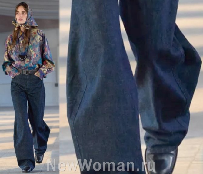С чем носить джинсовые синие брюки - женская одежда из Франции - синие джинсовые женские брюки, расклешенные от колена, с низкой посадкой и кожаным ремнем на талии, вместо пряжки - металлические полукольца-крепления. Подиум Lemaire, FALL 2023 MENSWEAR (Парижская Неделя моды)