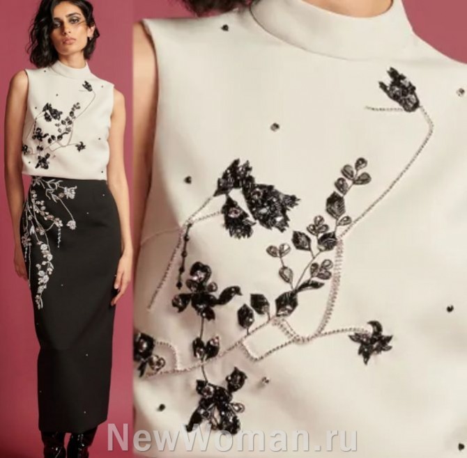 блузка цвета сливок без рукавов с воротником-стойкой и аппликациями черного цвета, украшенными бусинами и каменьями